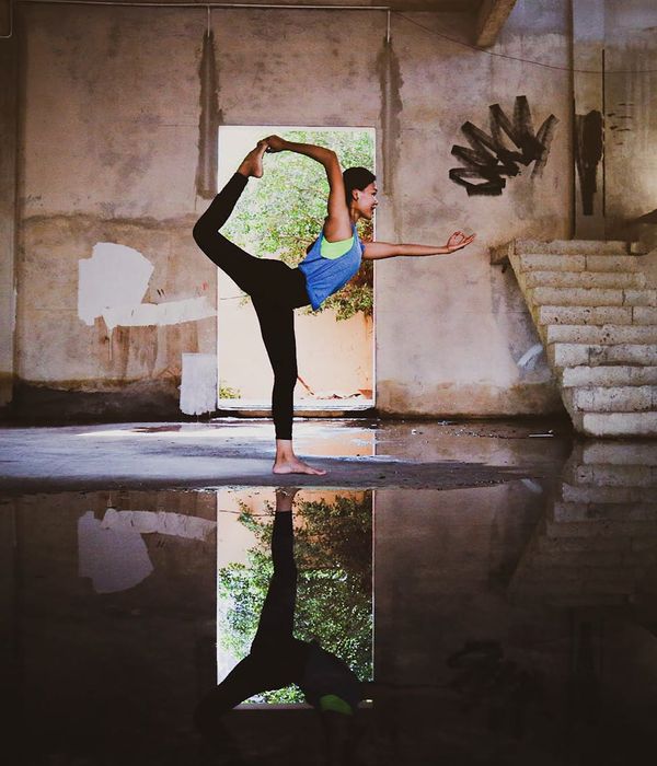Woman in a calm yoga pose in a dark room with golden light.